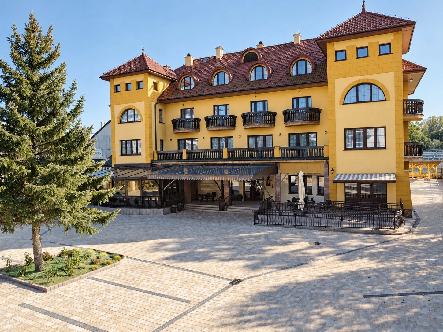 Budynek Domu Seniora Ruczaj z dziedzińcem i świerkiem