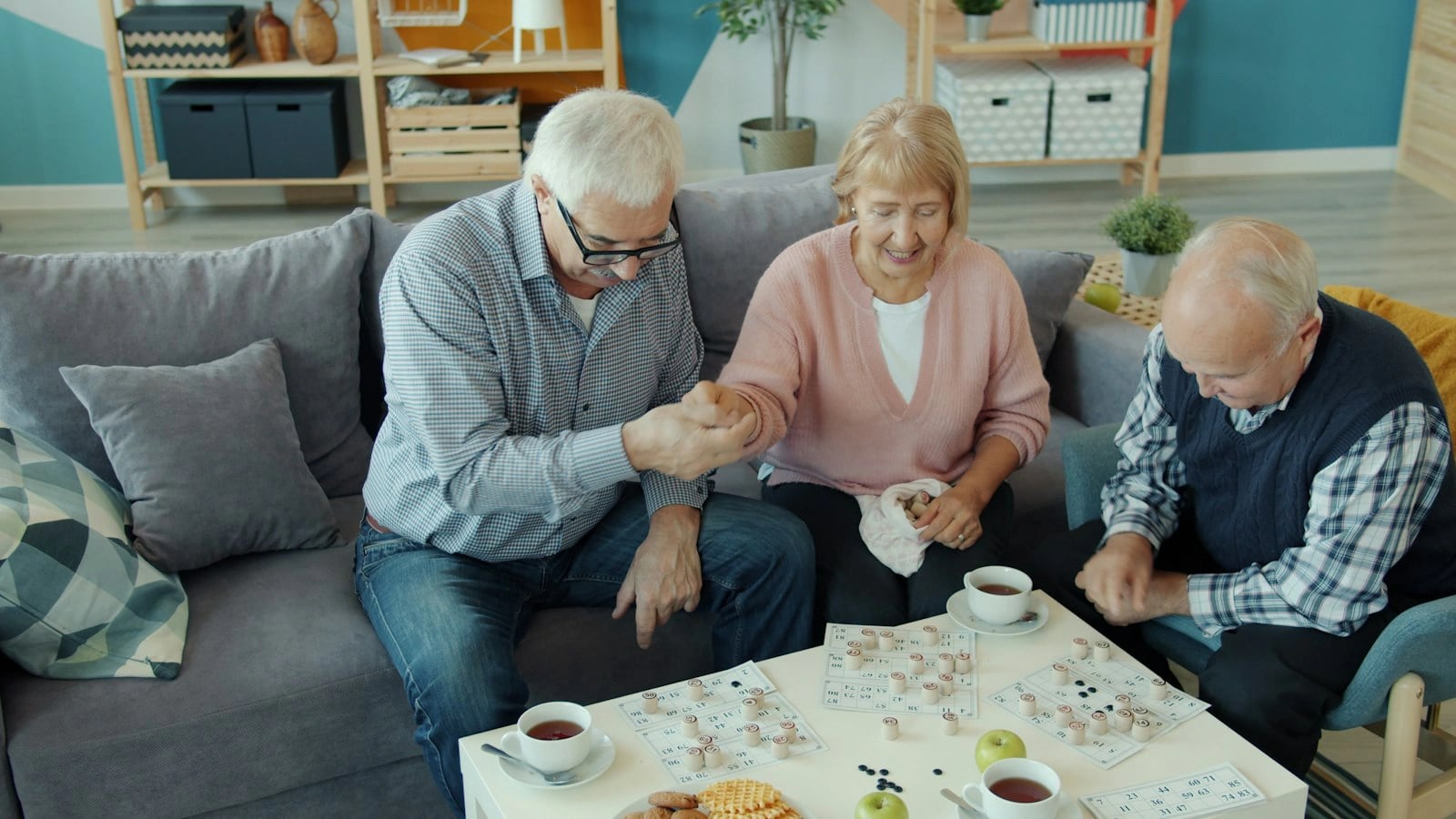Troje seniorów gra razem w grę planszową przy stoliku